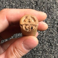 A wooden Metroid carved into a dowel