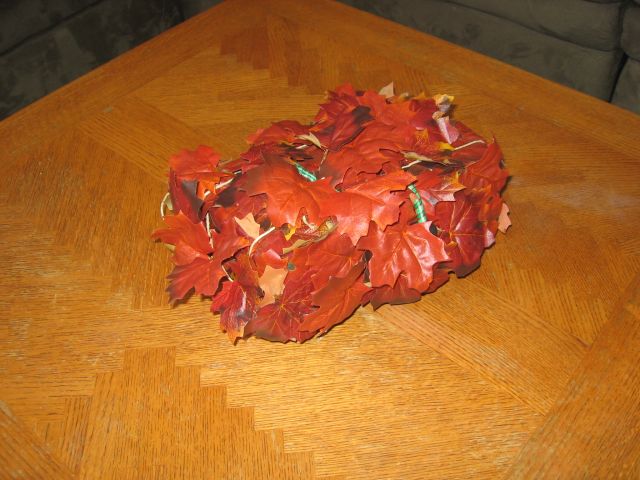 The leaf covered box sitting on a wooden table.