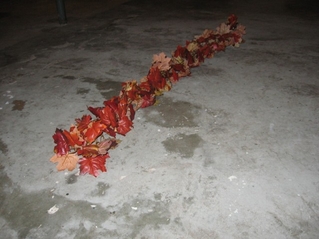 A string of fake brown plastic leaves laying on the ground.