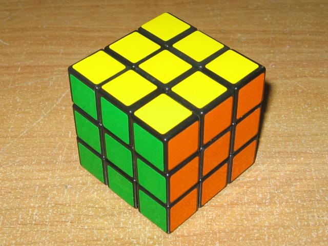 A Rubik's Cube sitting on a wooden surface.