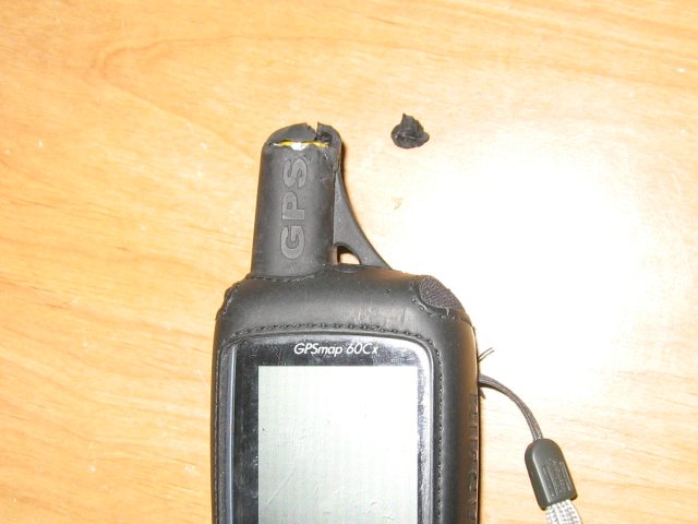A GPS on a wooden table, with a chunk of the rubber chewed off of the antenna.