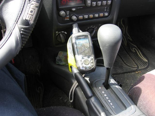 The cup and GPS inside of the car's cupholder, facing the driver.