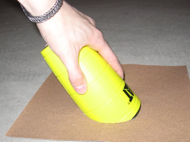 Holding the cut end against a sheet of sandpaper.