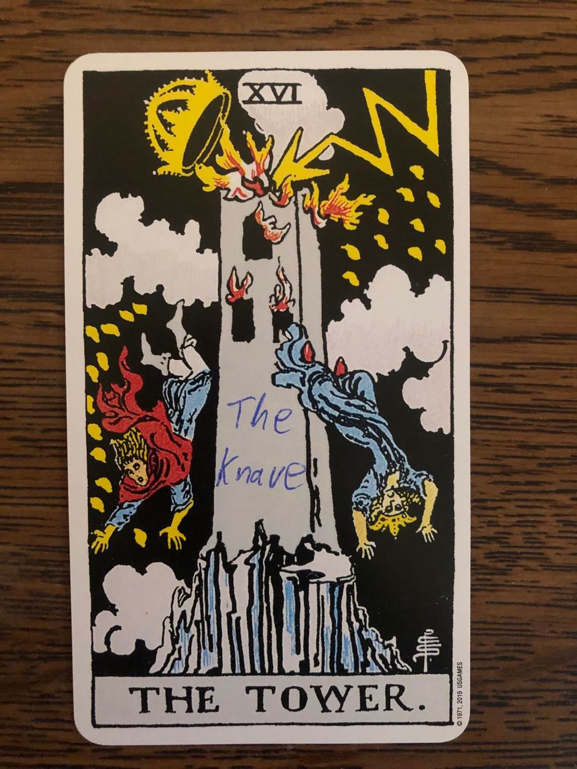 The tower card with the knave written on it, laying on a wooden desk.