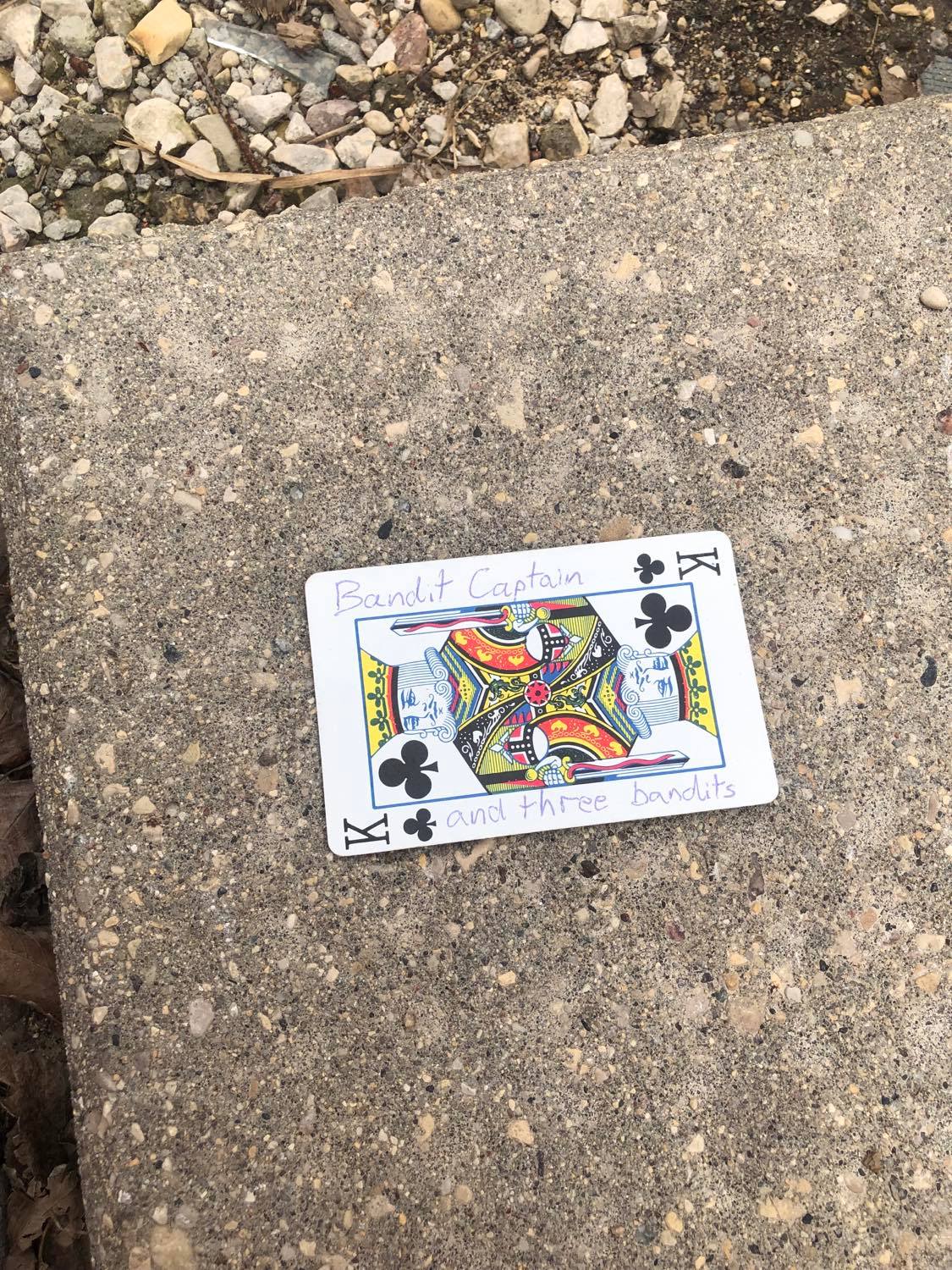 The king of clubs, laying on the ground before the creature.