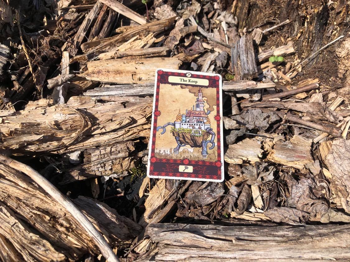 A castle on walking stilts, the card laying on the forest debris.