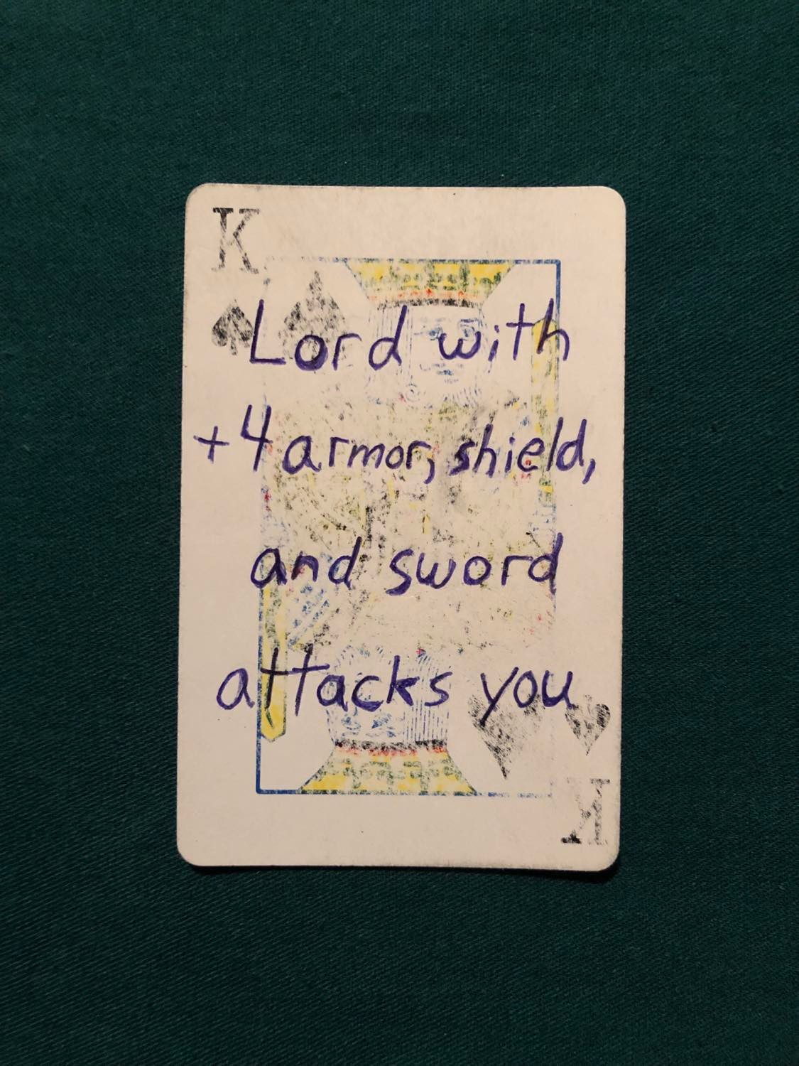 The king of spades, laying on a green fabric.