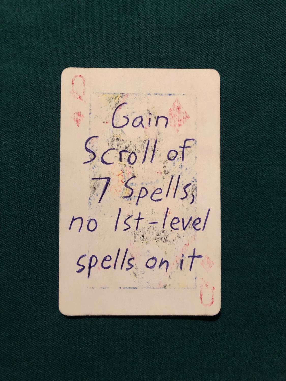 The queen of diamonds, laying on a green fabric.