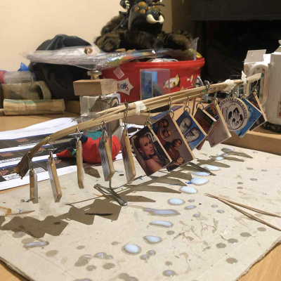 A temporary photo of the ornaments in mid-build, about a dozen of them hanging from a drying frame, dripping with varnish.