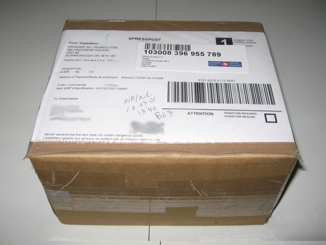 A cardboard box with mailing tag, address blurred out, from Kroeger, still thoroughly taped up, sitting on a white kitchen table.