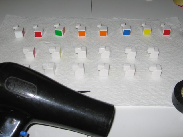 The pieces arranged on the paper towel, some now showing colour midway through flippng them over, with a hair dryer nearby.