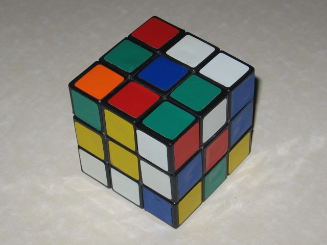A rubik's cube ona plain countertop, scrambled.