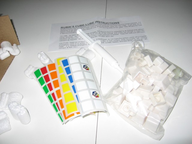 The contents spread out, showing the sheets of stickers, the lubricant, and the pieces in a clear bag.