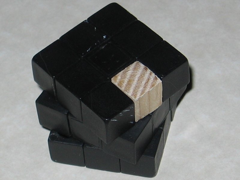 The Rubik's cube reassembled, with a wooden piece replacing one of the middle edge pieces.