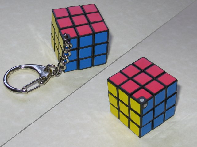 The cube removed from the package, and showing it with the keychain attached, and the chain removed with the holes filled in.