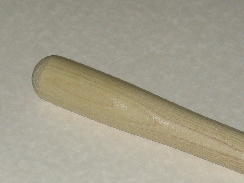 The end of a wooden shovel handle, laying on the countertop.