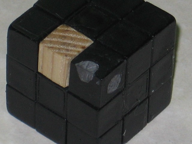 The corner cubie where the chain was, filled in with grey jb weld. One of the edge cubies is made of wood, as explained in another page.
