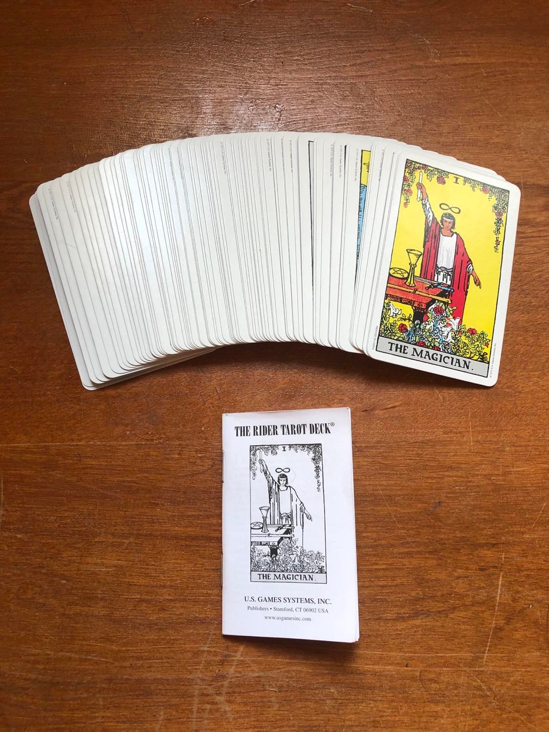 The cards faceup, tightly spread out so that only The Magician card is showing, with the instruction manual beneath.