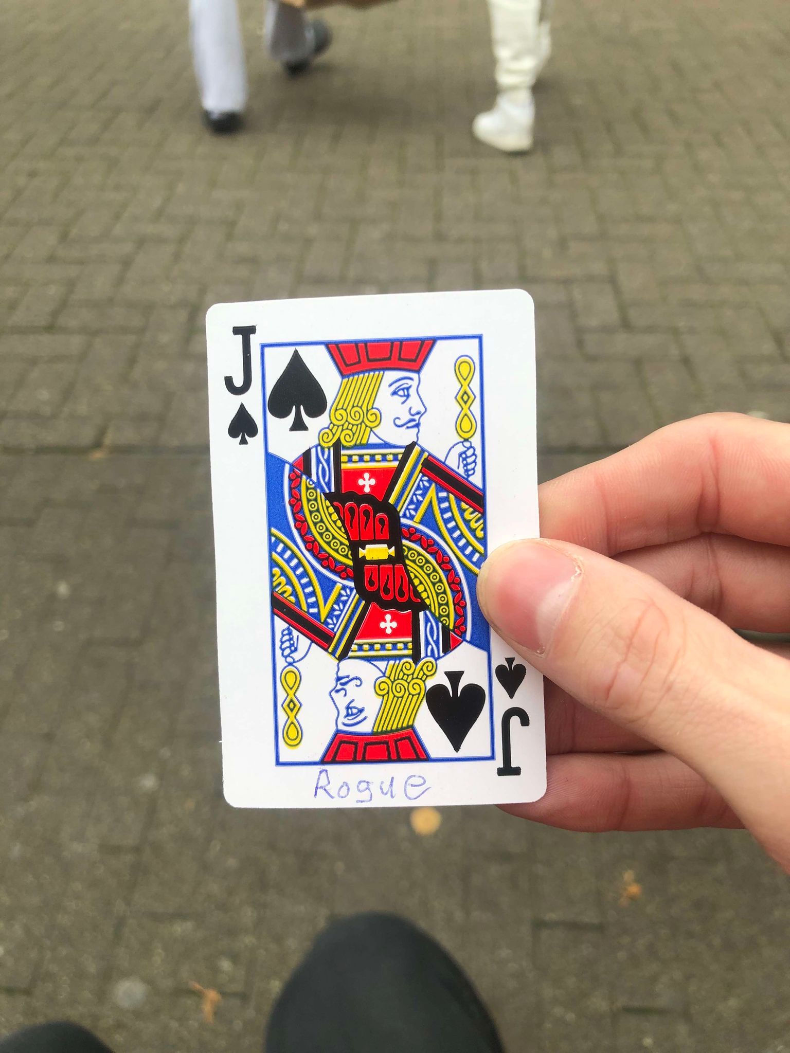 Sitting on a bench, a brick walkway in front of you, you hold the drawn card in front of you.