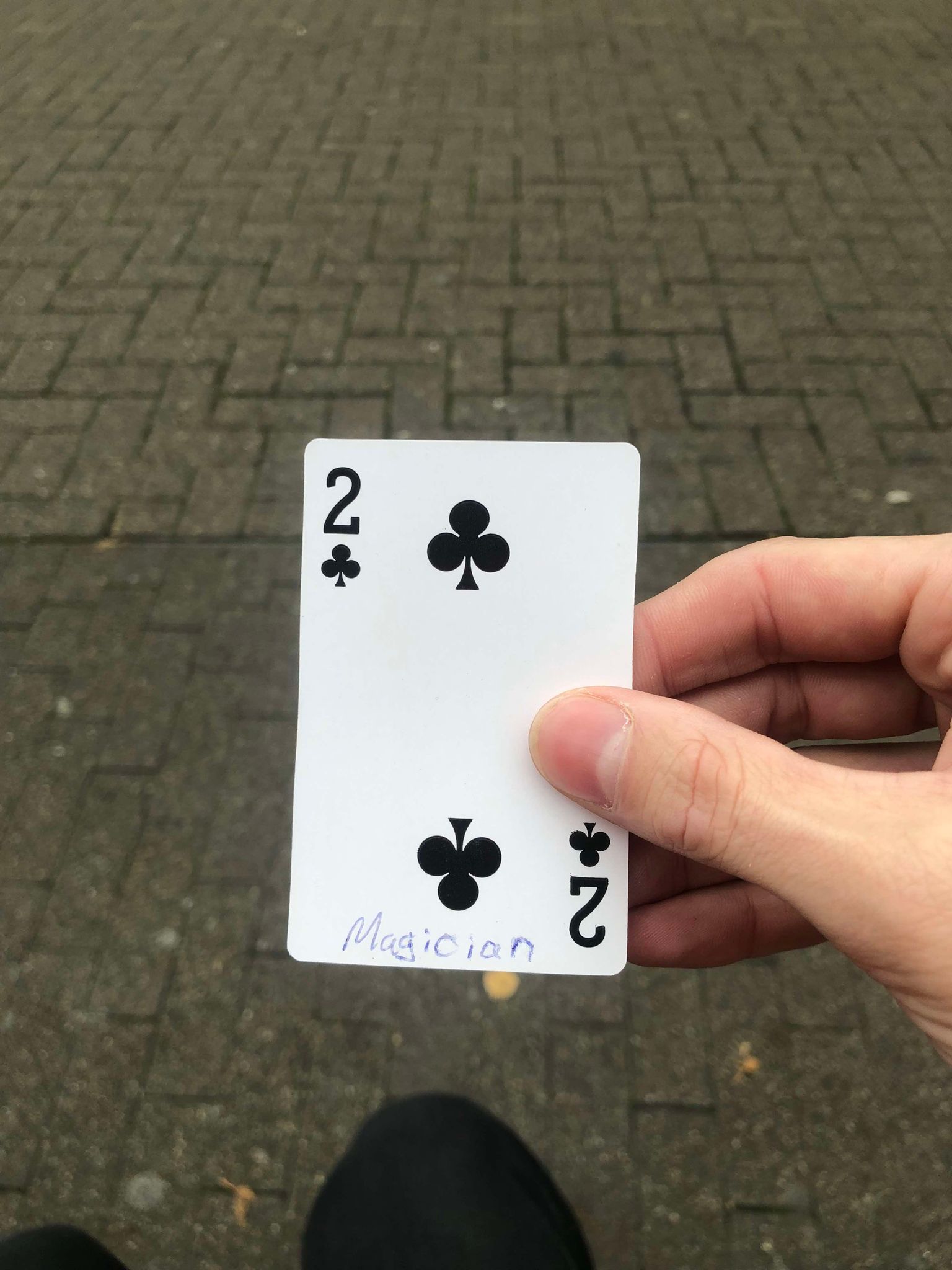 Sitting on a bench, a brick walkway in front of you, you hold the drawn card in front of you.