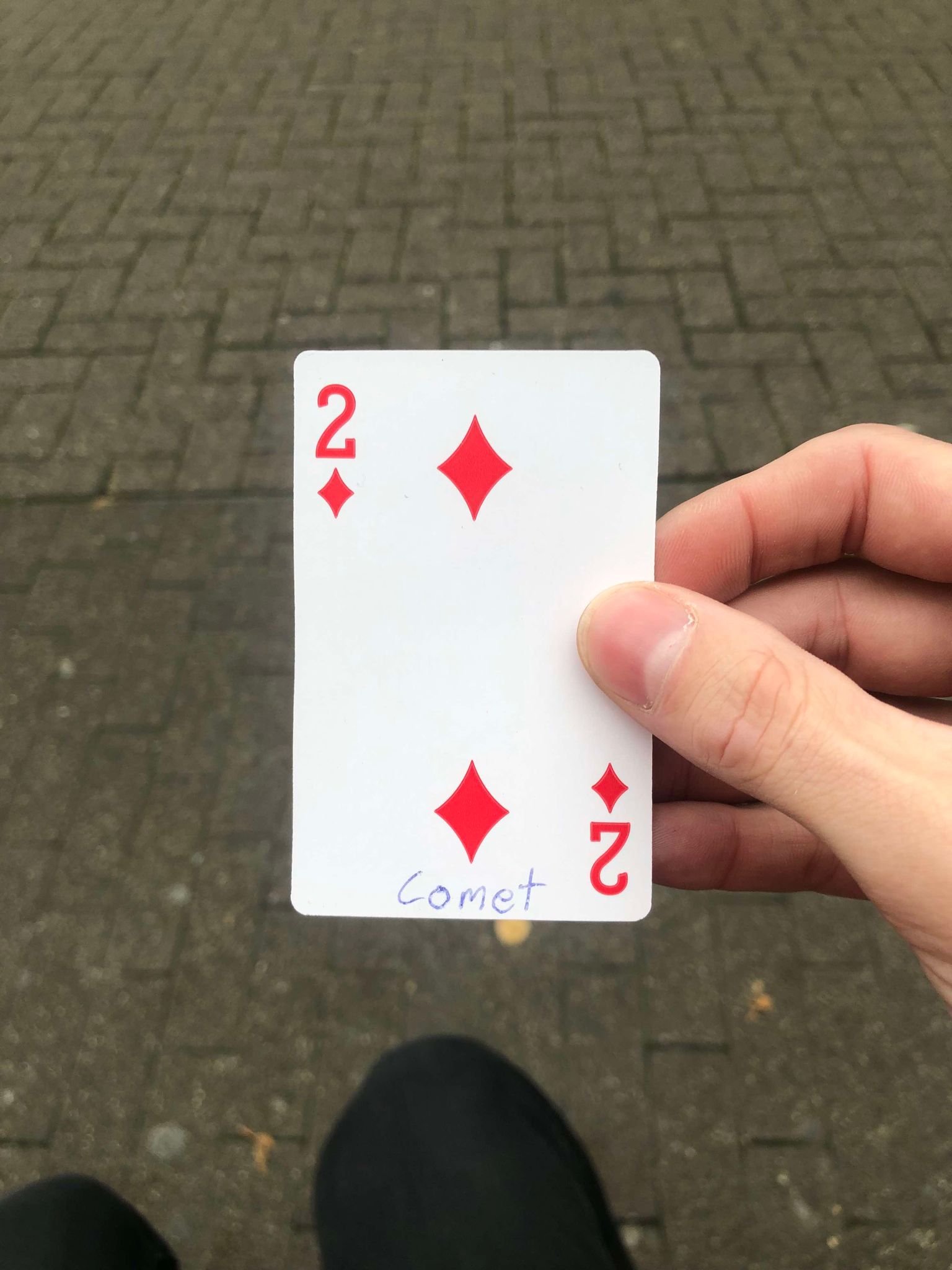 Sitting on a bench, a brick walkway in front of you, you hold the drawn card in front of you.