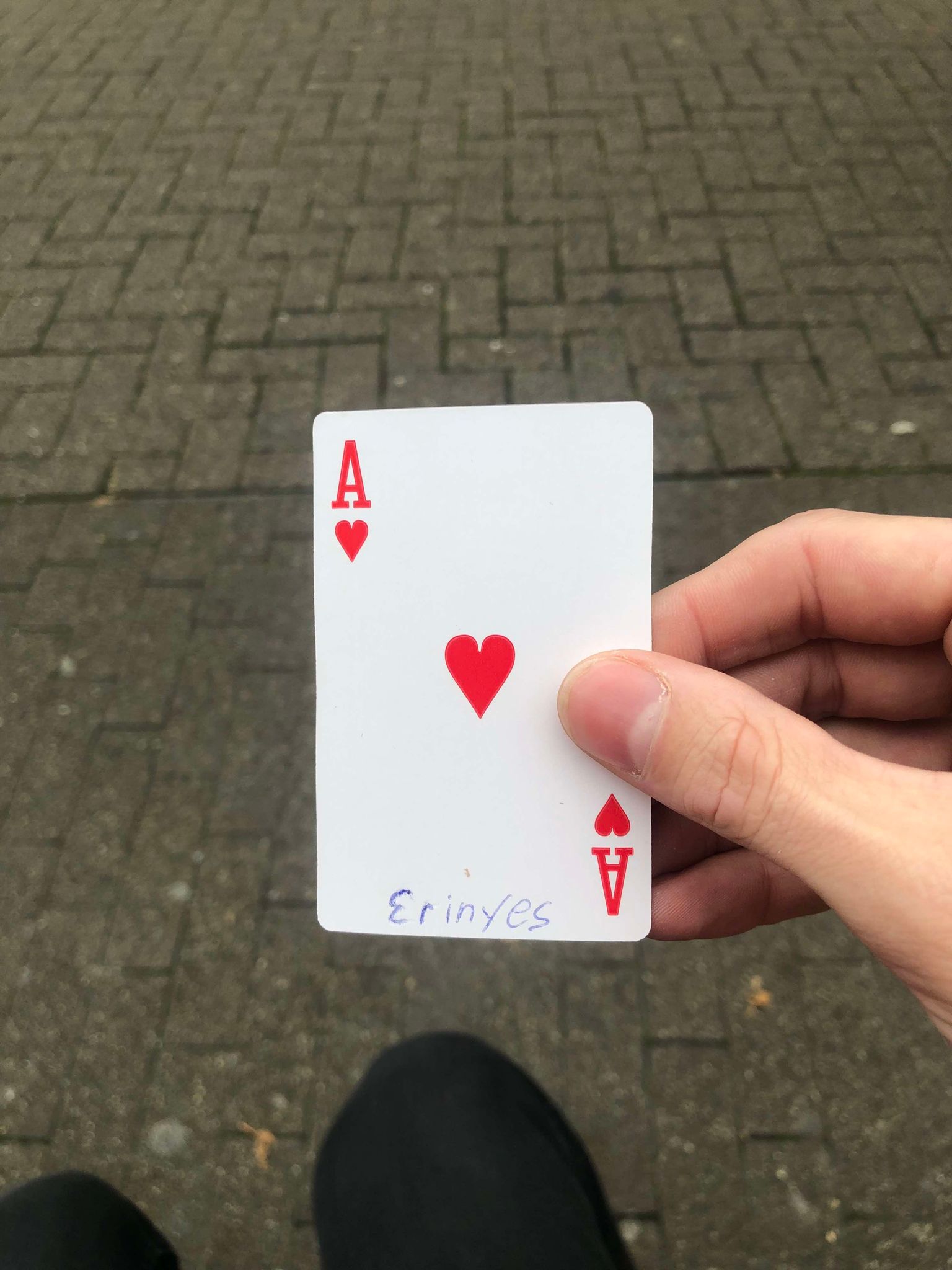 Sitting on a bench, a brick walkway in front of you, you hold the drawn card in front of you.