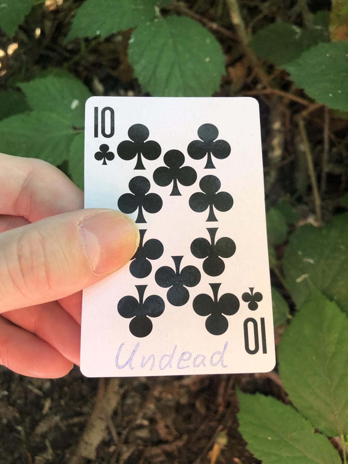 The ten of clubs with the word undread written on it, held above the brush.