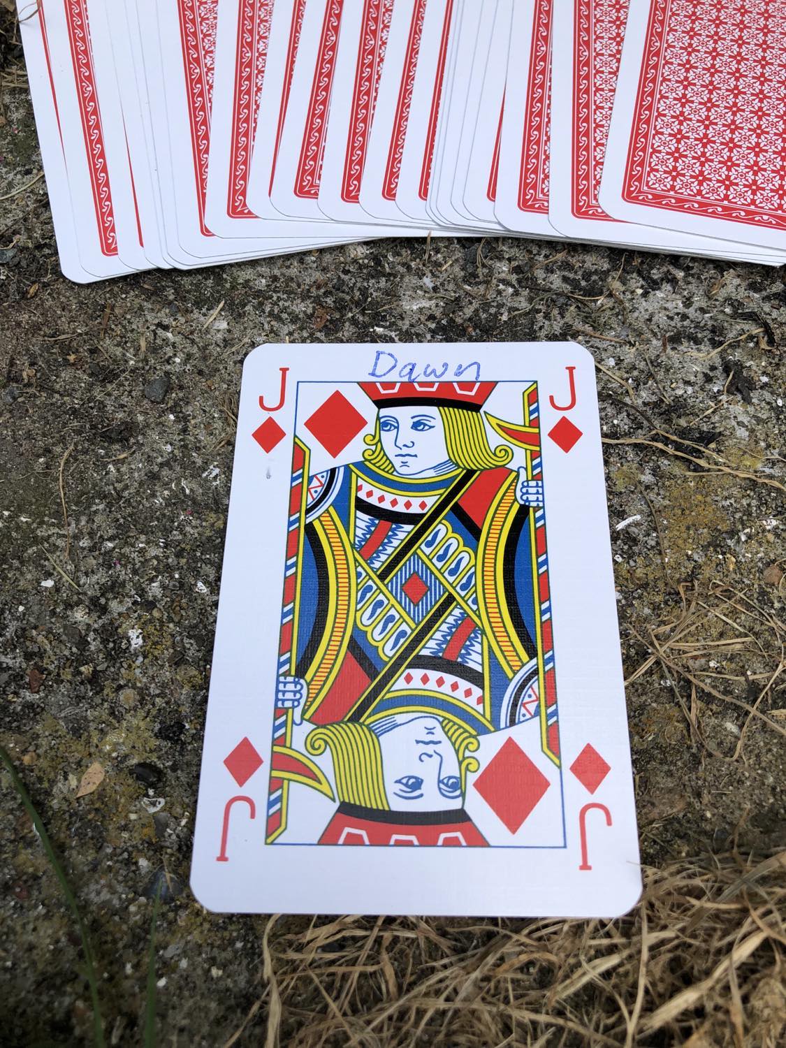 The jack of diamonds with the word Dawn written on it, laying on the bridge support.