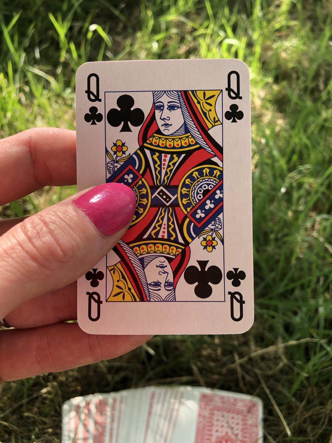 The queen of clubs, held up from the drawn out cards.
