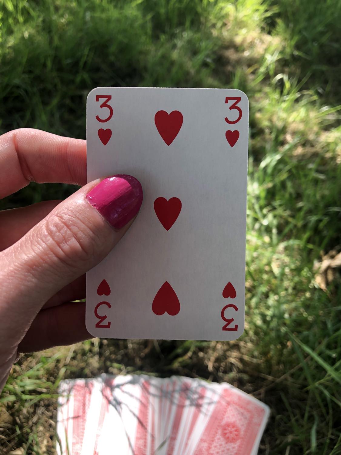 The three of hearts, held up from the drawn out cards.