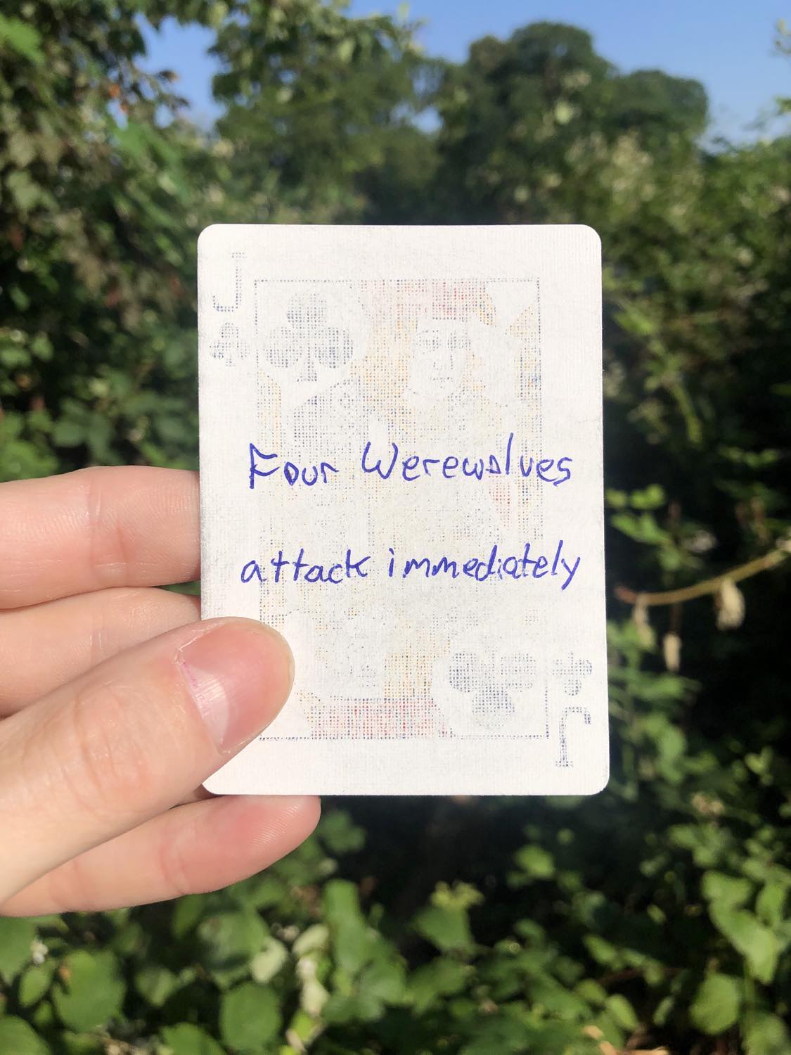 The jack of clubs, held with the trees and foliage behind. Four Werewolves attack immediately.