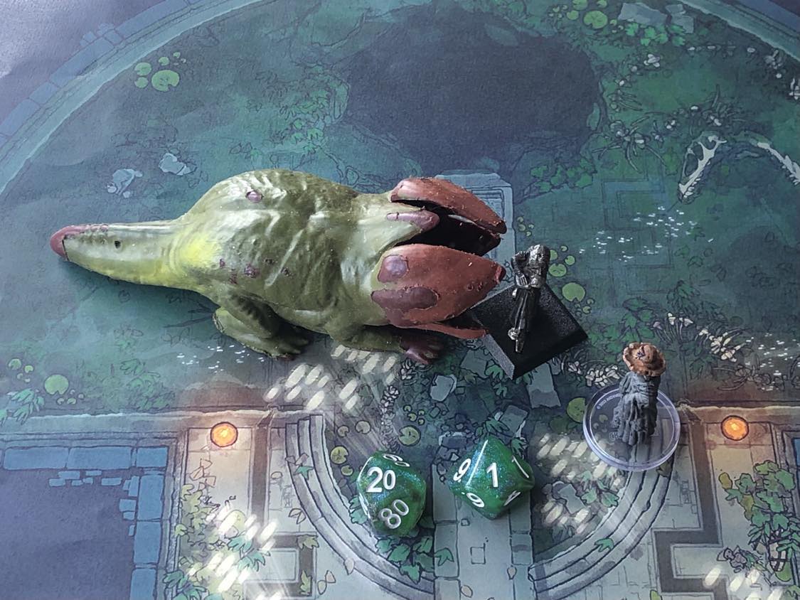 The battle map from above, with the monk fully attacking the creature, and the sorcerer rolling a pair of d10 dice to determine the wild magic surge.