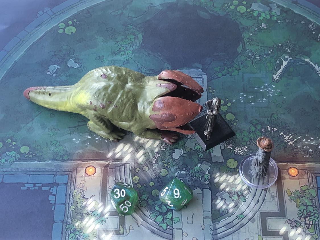 The battle map from above, with the monk fully attacking the creature, and the sorcerer rolling a pair of d10 dice to determine the wild magic surge.