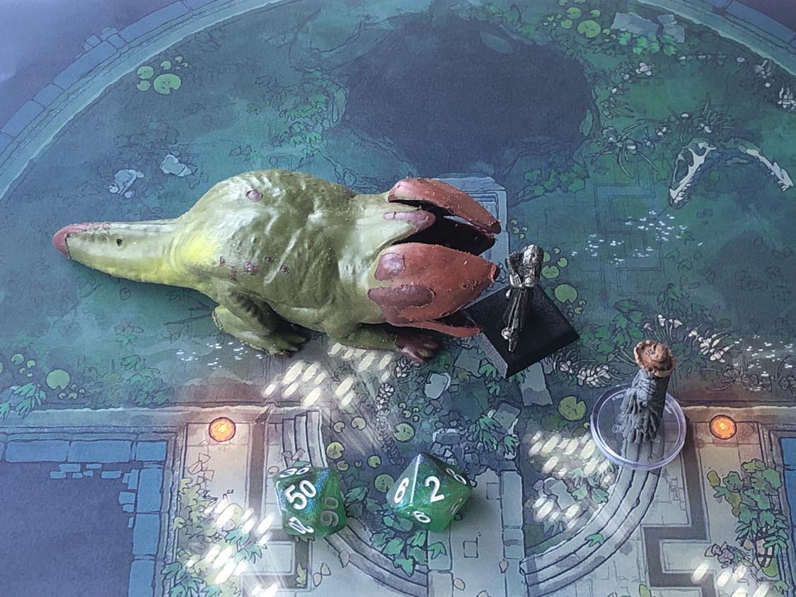 The battle map from above, with the monk fully attacking the creature, and the sorcerer rolling a pair of d10 dice to determine the wild magic surge.